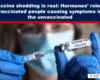 Close-up of a vaccine syringe drawing from a vial labeled COVID-19 Vaccine, gloved hands, with a masked person blurred in the background; top banner discusses vaccine shedding.