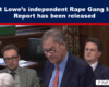 News banner declares 'Rupert Lowe’s independent Rape Gang Inquiry Report has been released'; in a wood-paneled hearing room, a man in a blue suit and red tie speaks while two other suited men listen nearby.