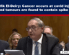 Television news screenshot of a man in a suit speaking at a hearing; headline reports cancer at covid injection sites and spike protein in tumors.