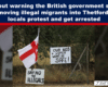 Protest scene with handwritten signs on a chain-link fence: 'Our kids and women won’t be safe' and 'Say no to illegals', plus a red-and-white flag nearby.